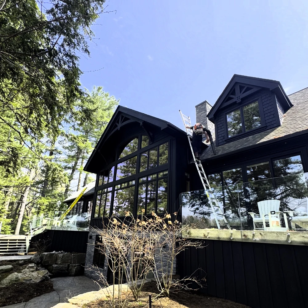 Brite Surface Cleaning professional using a leafblower to clean out gutters on a muskoka cottage